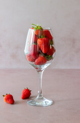 A wine glass with strawberries on a pink background. Design. Minimalism. Healthy eating. Diet. Vegetarian food.