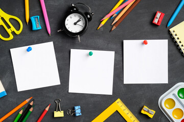 Memo sticky notes and school stationery on black board background. Flat lay, top view. Back to school concept.