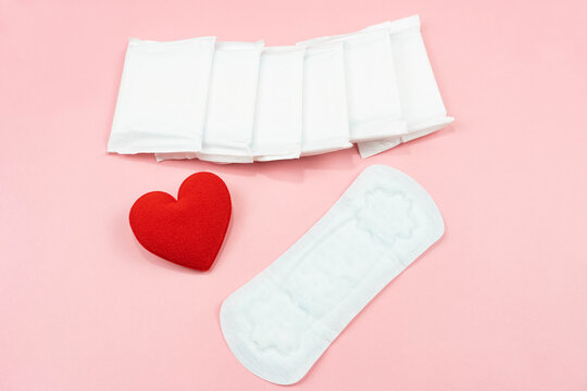 Top view white sanitary napkin or pad and,red heart on pink background. Woman hygiene, Concept of critical days, menstruation,health care