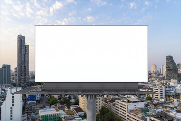 Blank white road billboard with Bangkok cityscape background at sunset. Street advertising poster, mock up, 3D rendering. Front view. The concept of marketing communication to promote or sell idea.