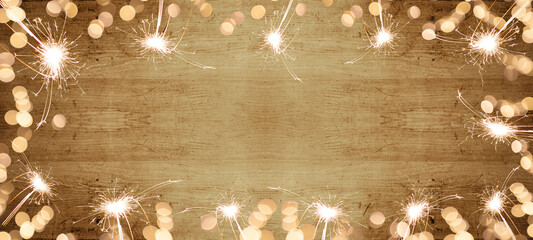 Frame of lights bokeh lights flares and sparkler isolated on rustic brown wooden texture - holiday...