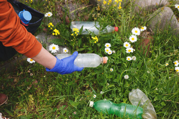 volunteer young woman collecting garbage and picking up plastic bottle waste at dirty nature summer...