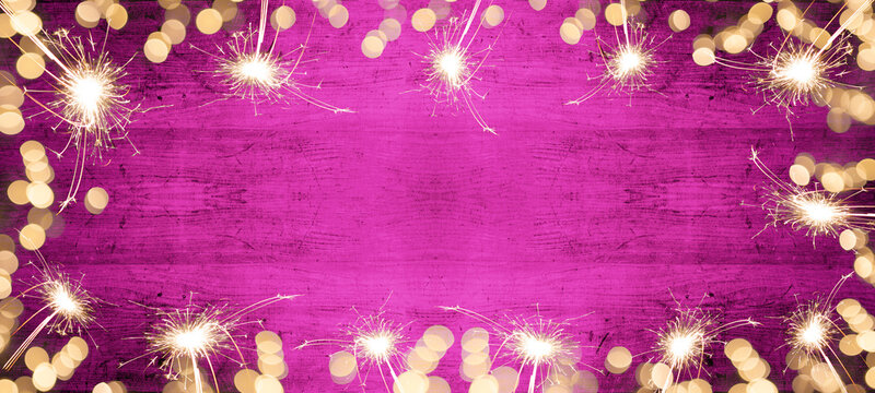 Frame of lights bokeh lights flares and sparkler isolated on pink painted wooden texture - Holiday New Year's Eve Silvester celebration background banner 