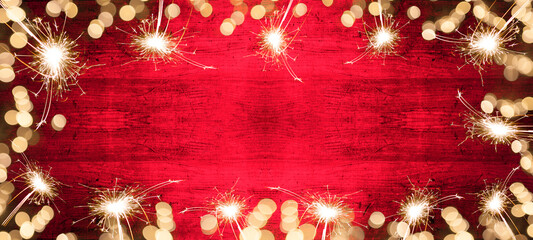 Frame of golden bokeh lights flares and sparkler isolated on red painted wooden texture - Holiday...