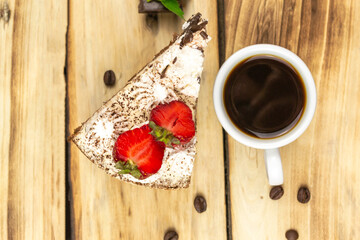 A triangular piece of tiramisu decorated with strawberries, a cup of coffee, coffee grains.