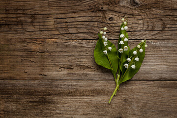 Beautiful bouquet of lilies of the valley flowers on an old vintage wooden table with cracks. Copy space for text.