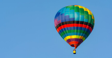 Balloon flying high in the sky. Balloon basket with people. Aeronautic sport. Burning gas. Bright multi-colored balloon. Romantic trip. Free space for text.