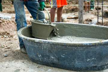 Motion blurred hand of worker carrying the bucket of mixed cement out of the wagon and delivers to colleagues at the construction site