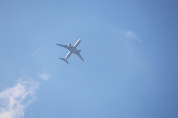 White airplane flying in the blue sky with clouds, bottom view. Two-engine commercial plane during taking off