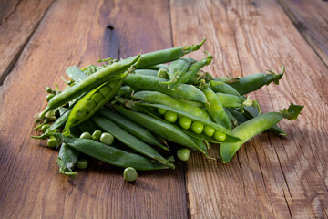 open pods of green peas on a wooden table close-up, harvest from the garden