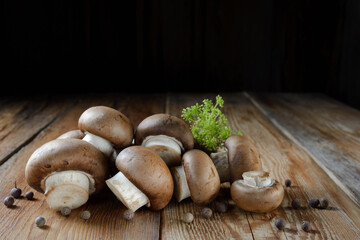 Royal mushrooms champignon whole and cut into pieces, scattered peppers, close-up on a wooden background, rustic style