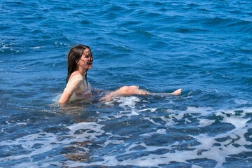 Laughing teen girl having fun in the sea, playing with sea wave