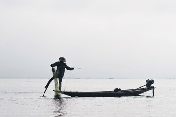 Traditional fisherman on a boat on Inle lake. Leg Rowing Fishermen with net on boat Inle Lake Myanmar Burma