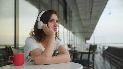 Young depressive woman in headphones listening to music