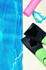 Small flippers and mask on the edge of the swimming pool. Vacation and holidays. Copy space for advertisement text