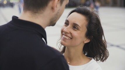 Portrait of attractive couple standing at the city street and looking to each other