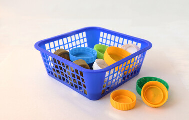 Plastic container with colorful plastic beverage lids on a white background, close-up, side view -...