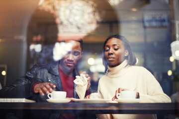 Dark skinned man and woman sitting together in coffee shop interior while rest after walking outdoors and drink cafe, two friends relaxing after strolling in cold winter day during weekend