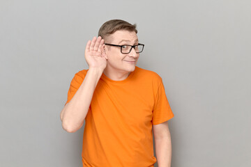 Cheerful man is placing hand near ear and eavesdropping conversation