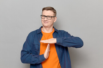Happy man is showing timeout gesture with hands over chest and smiling