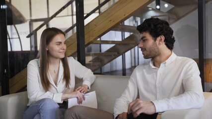 Young elegantly dressed couple sitting on a white sofa and talking.