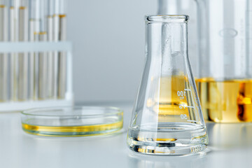 Laboratory glassware with yellow oily liquid on grey background
