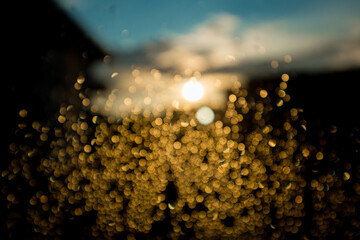 Beautiful sunset city bokeh. Abstract background. Water drop on the glass against the blurred building city silhouettes.