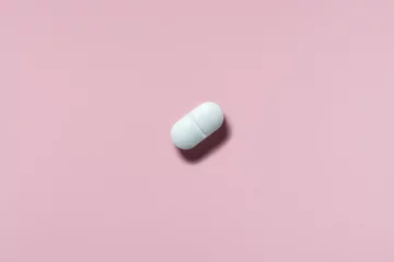 Gordijnen medicine, healthcare and pharmacy concept - white pill or capsule lies on pink background top view copy space © Oksana Smyshliaeva