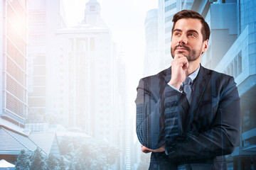 Young handsome businessman in suit with hand on chin thinking how to succeed, new career...