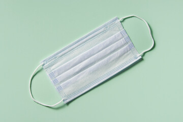 medicine, healthcare and pharmacy concept - medical mask lies on mint green background top view copy space