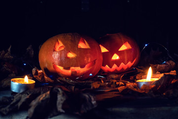 Two glowing pumpkins in the dark in the forest, candles lit around them. Beautiful background for Halloween.