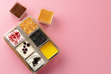 Mousse desserts in square plastic boxes with different toppings on pink table