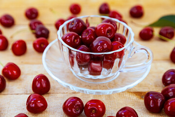 Ripe cherries in a cup on a wooden background,