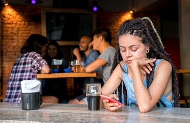 A girl alone with her phone in a bar