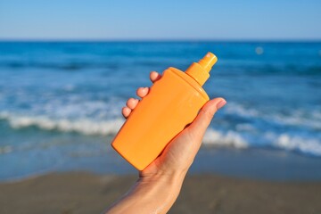 Bottle with sunscreen lotion in hands of woman on the beach, \