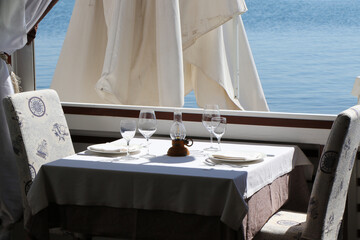 Table set in a restaurant in front of a window overlooking the sea