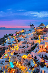 Plakaty  Słynne greckie kultowe selfie spot turystyczna wioska Oia z tradycyjnymi białymi domami i wiatrakami na wyspie Santorini wieczorem niebieska godzina, Grecja