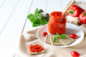 Balkan traditional dish ajvar, lutenitza, pingjur, with bread on a plate on white wooden table. Serbian traditional food