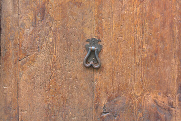 Fondo de madera de una puerta antigua con una aldaba de la misma época 
