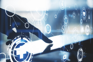 Hand touching digital tablet with glowing medical hologram.