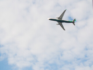 Passenger airplane takes off against the blue sky with clouds.