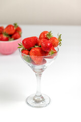 Strawberry berries in a glass goblet on white background by the window. Summer concept