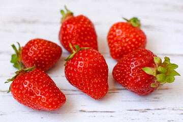 Red ripe strawberries on a light wooden background. Closeup.