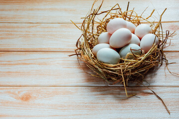 White eggs in hay nest on wooden table background