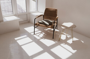 Empty white sunny room with wicker chair and table. Minimalist design