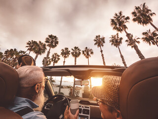 Happy senior couple having fun driving on new convertible car - Mature people enjoying time together during road trip tour vacation - Elderly lifestyle and travel culture transportation concept - obrazy, fototapety, plakaty