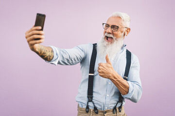 Senior man using mobile smartphone and listening music with airpods - Happy mature male having fun...