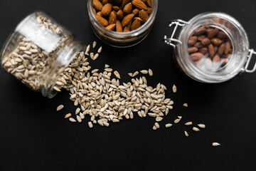 Sunflower seeds scattered on the black table from a jar. Sunflower seed is a healthy vegetarian...