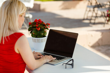 Happy woman planning vacations on line searching information in a laptop in a resort or hotel in the beach