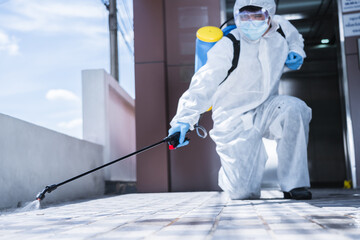 Man in virus protective suite and mask spraying alcohol cleaning covid19 infected area, Virus...